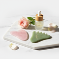 Rose quartz and jade gua sha stone set on white background